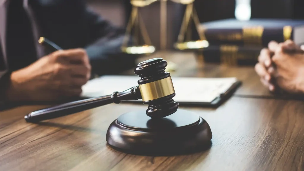 A judge's gavel resting on a wooden table with legal documents and scales in the background.