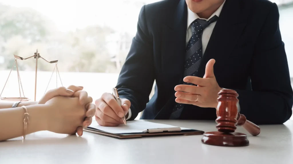 A professional in a suit discussing legal matters with a client, with a gavel on the table, symbolizing law or consultation.